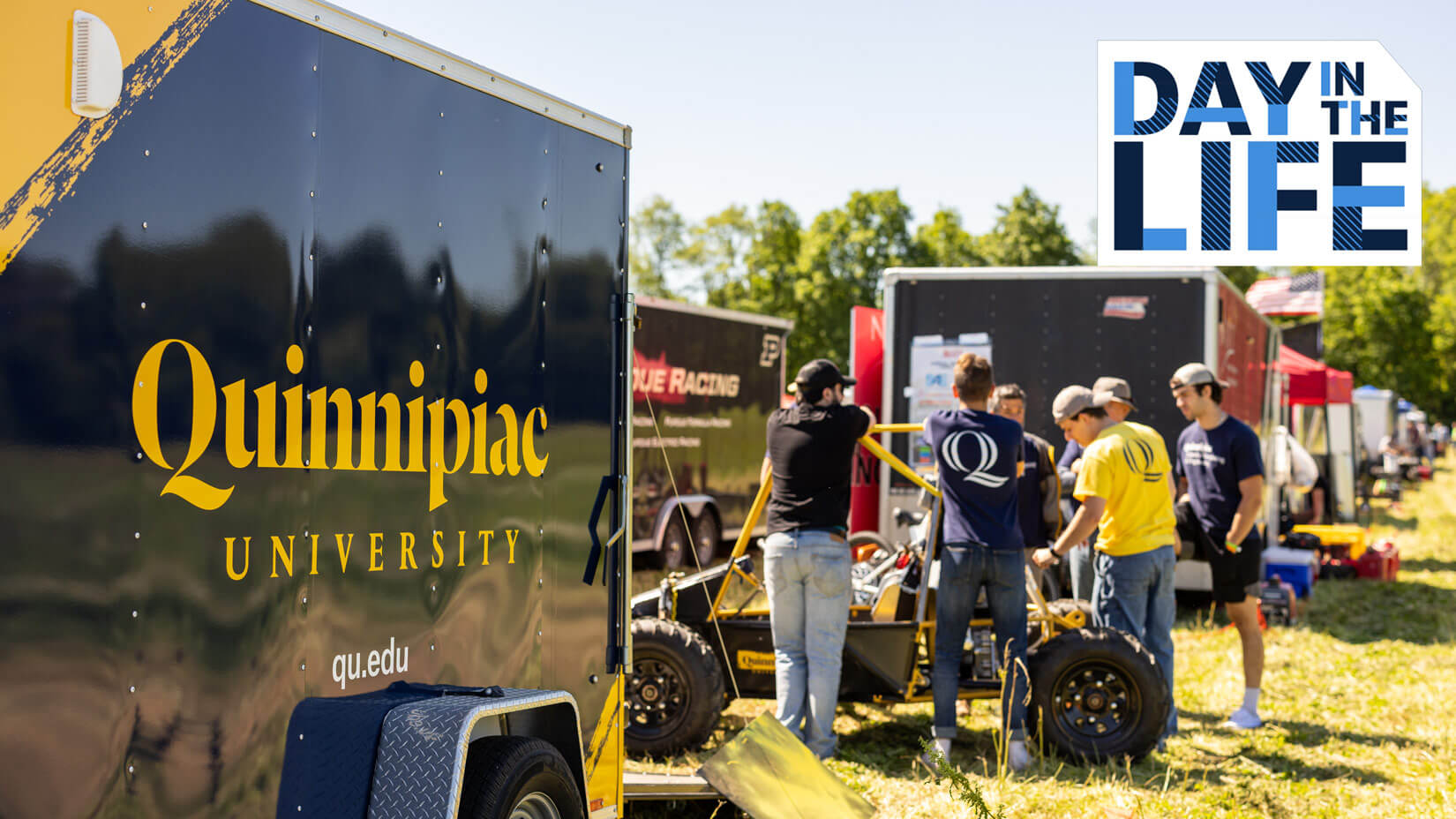 Students working on the Baja vehicle outside by the trailer, plays video