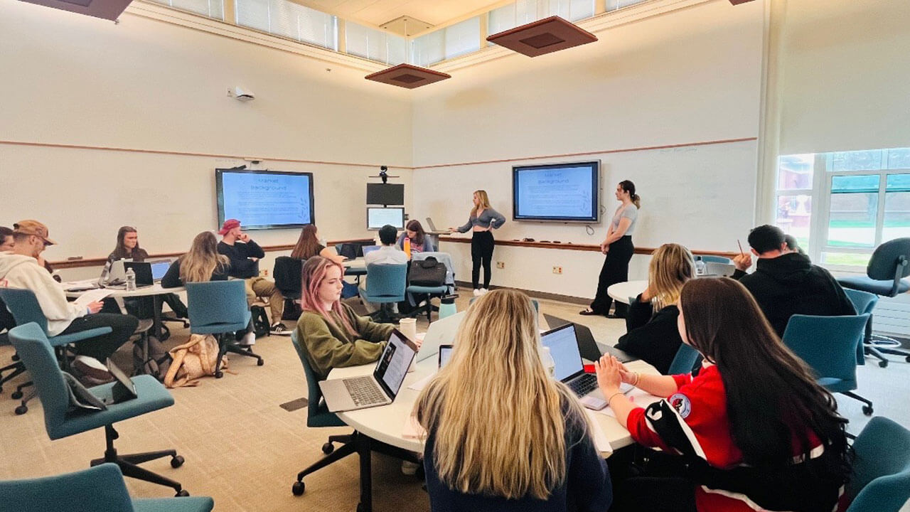 A photo of 2 students presenting their capstone project to their class