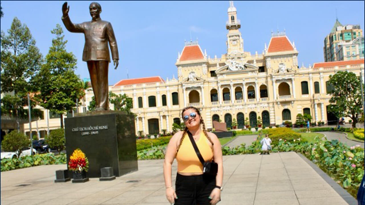 A woman posing in front of a statue and a building