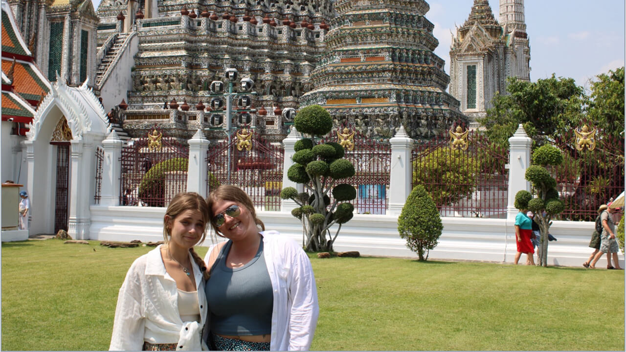 Two women posing for a photo in front of a building
