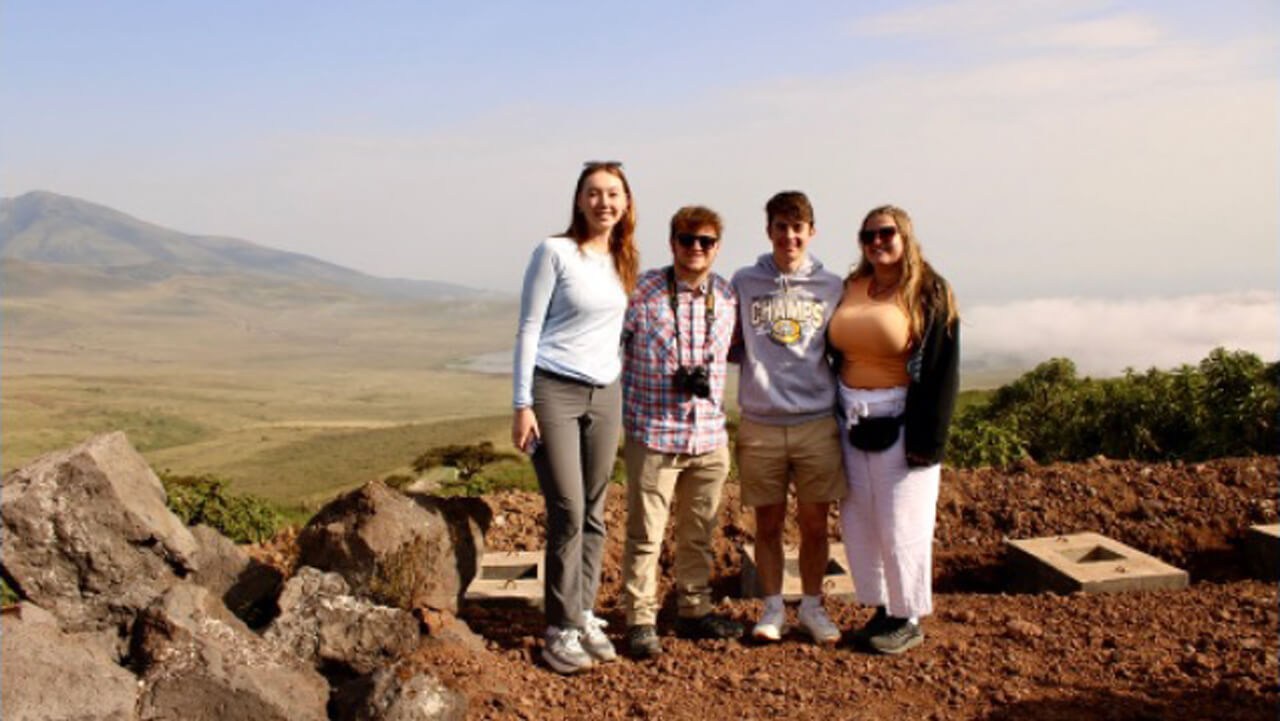 A group of four people posing for a photo on top of a hill