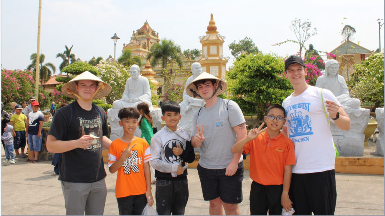 A group of six people posing in front of statues and a building