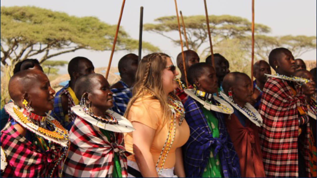 A group of people standing together outdoors, some wearing traditional African attire