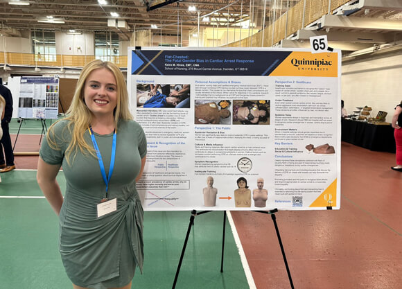 Student posing next to her presentation poster