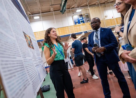 A student presenting their poster to a group of people