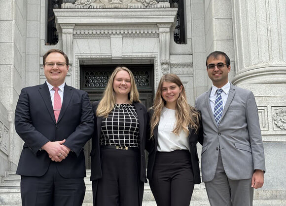 4 law students standing outside of a courthouse, posing for the picture