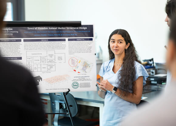 Student presenting project poster to group of people