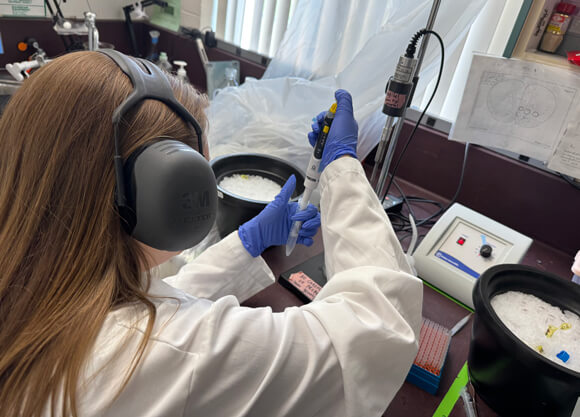 Women in a lab using a dropper to move liquid into a test tube