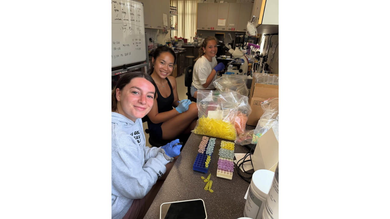 Three students smiling for a picture while in a lab