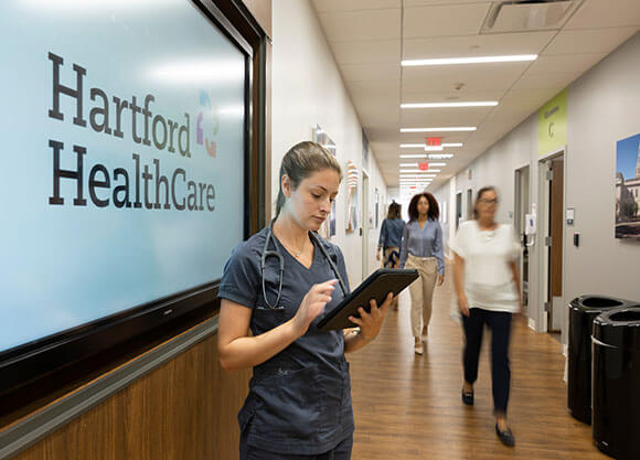 Employee standing in front of Hartford Healthcare sign